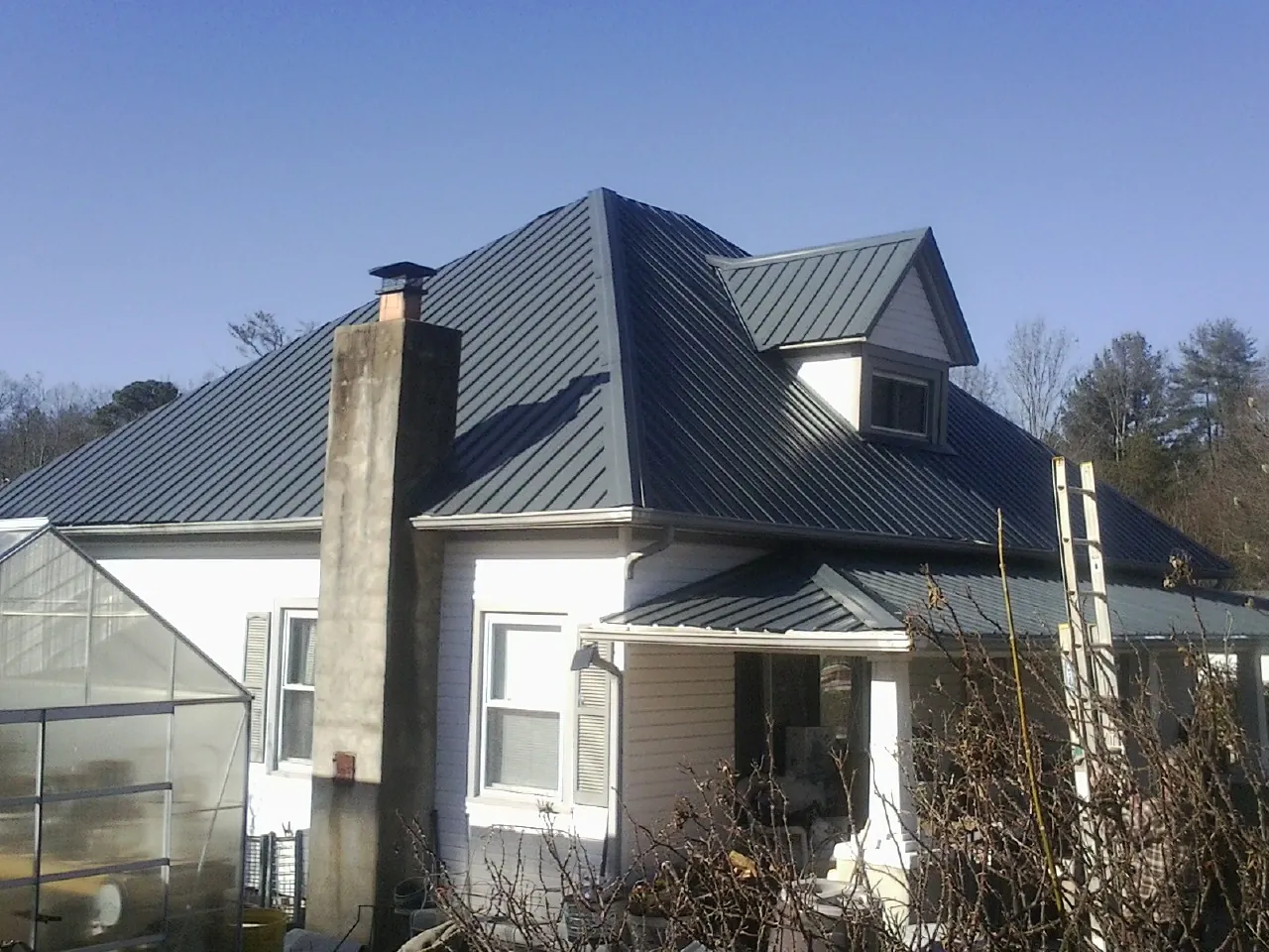 Dark blue standing seam metal roof on a white farmhouse with dormer — Slate & Tile Roof Repair by Roofing Brothers in Cashmere