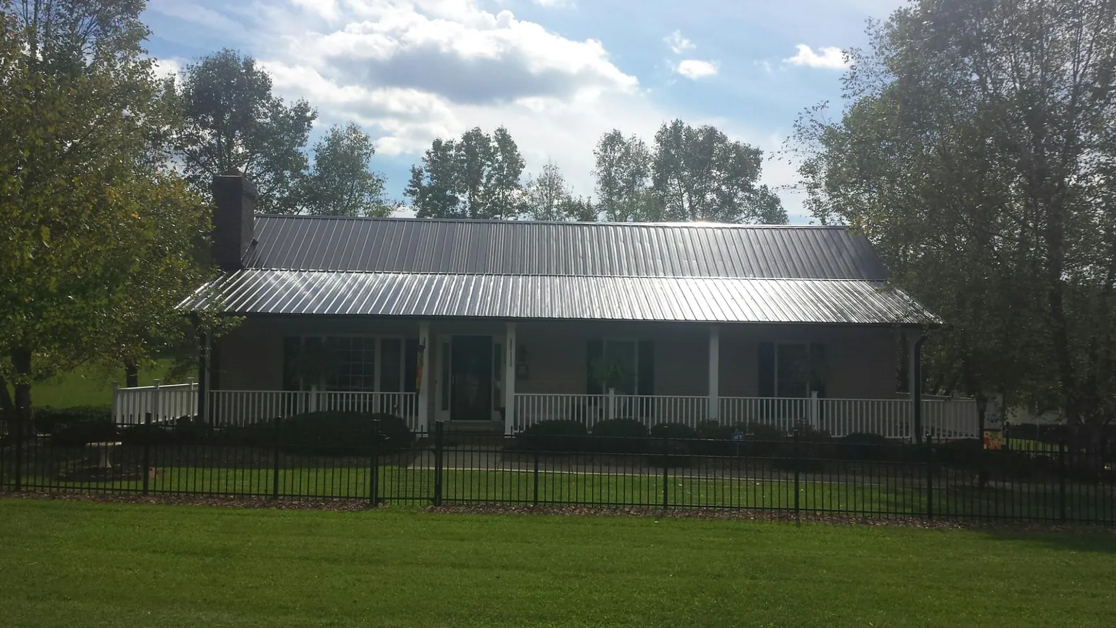 Gray metal roof on a brick ranch with a full width front porch — Gutter Guard Installation work by our crew in Cashmere