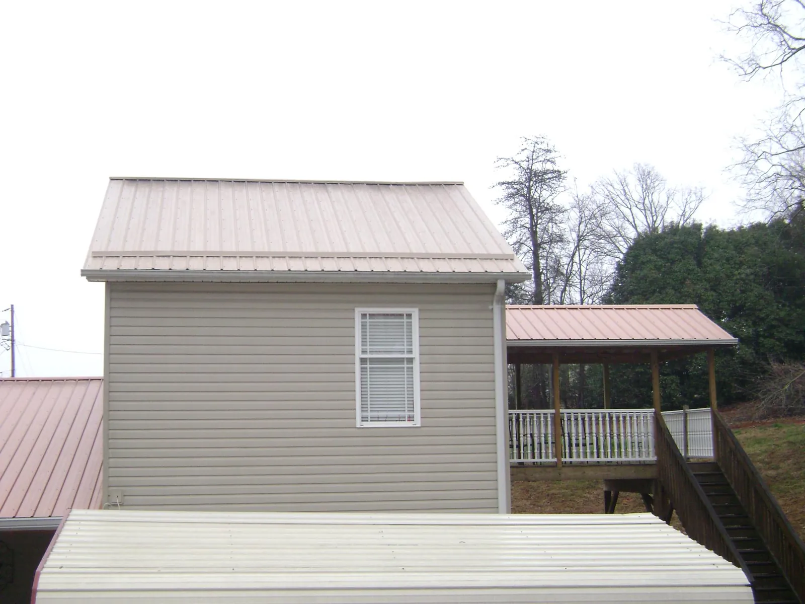 Tan metal roofs on a two story addition and attached porch, from a Roof Replacement job in Cashmere