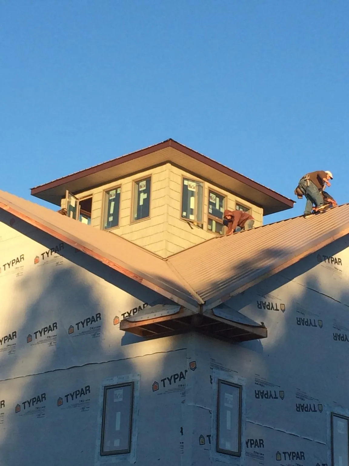 Roofers working around a rooftop cupola on a new metal roof at sunset — Roof Waterproofing in Cashmere by Roofing Brothers